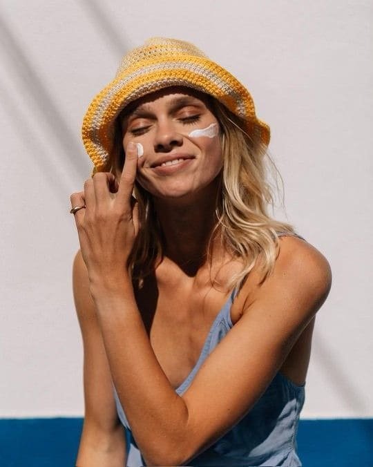 women applying sunscreen on her face 